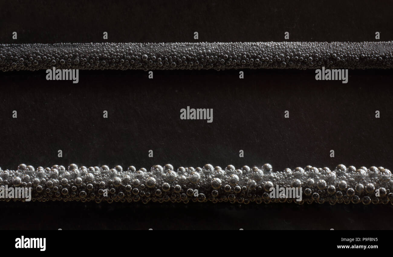macro photo of electrolysis of water. The bubbles on the top are oxygen. the one's on bottom  are hydrogen. Stock Photo