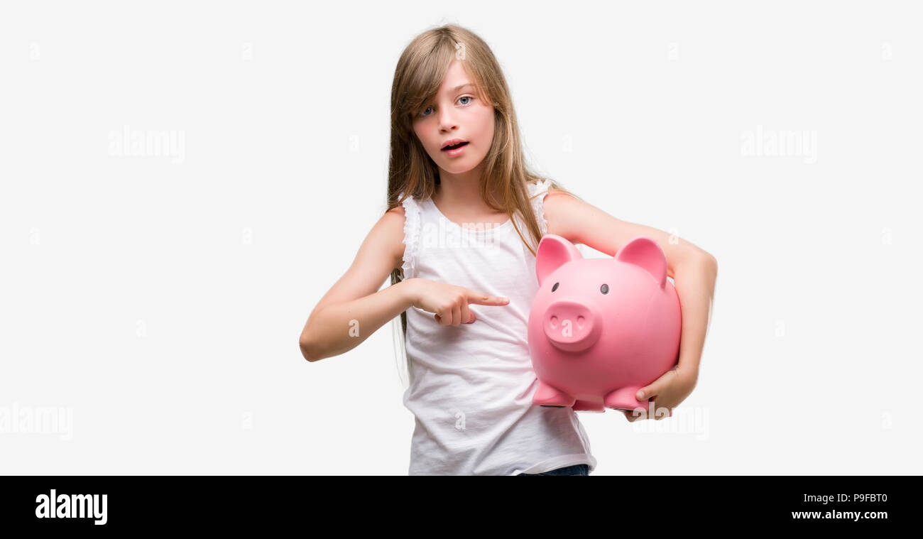 Young Blonde Toddler Holding Piggy Bank Very Happy Pointing With