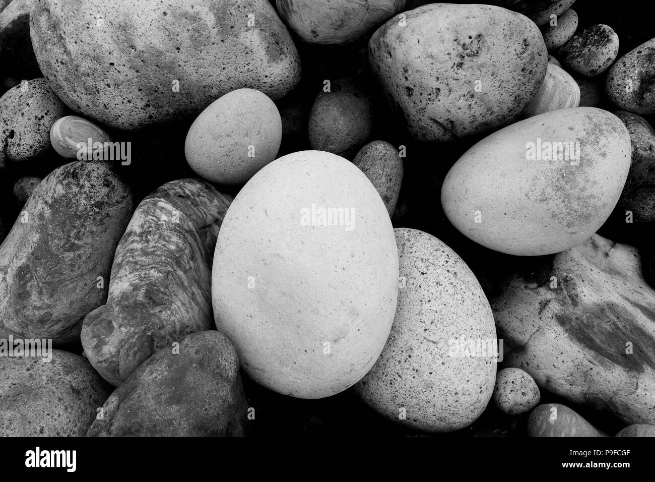 Rounded pebbles /  stones / boulders on a beach in the Azores in black and white Stock Photo