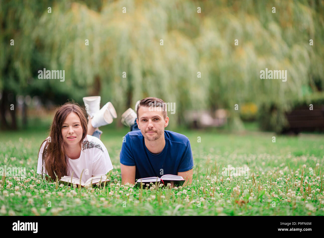 Молодые расслабляются. Man reading a book on the grass.