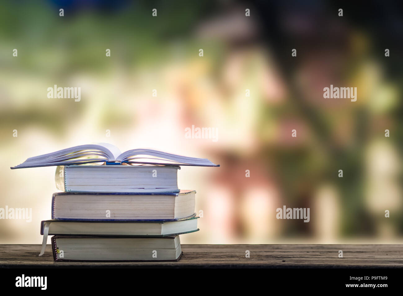 Open Vintage Book On Stack Books On Table With Blurred Green