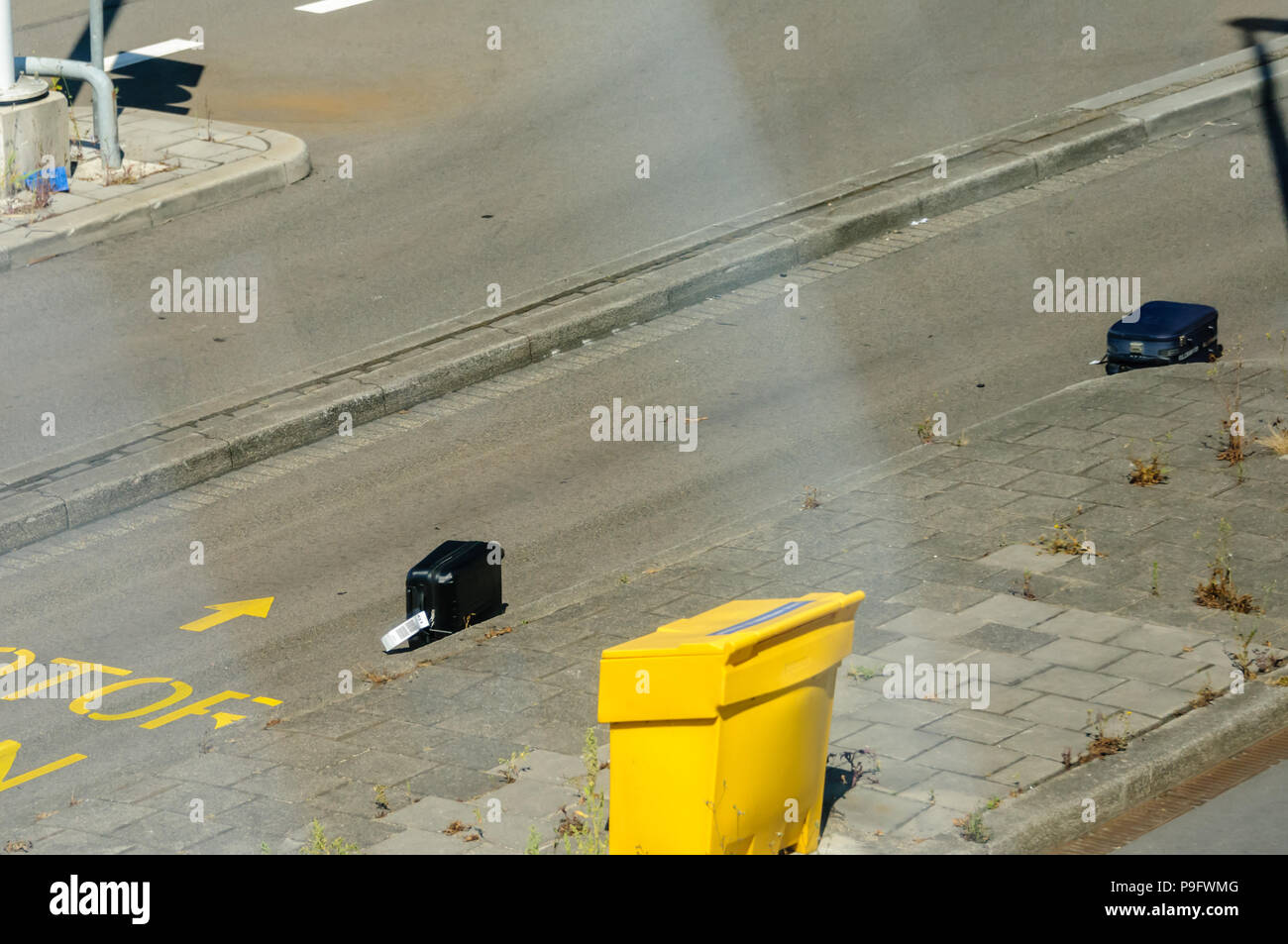 Passenger luggage suitcases lie on an airport road after falling off a baggage truck, will be lost luggage. Stock Photo