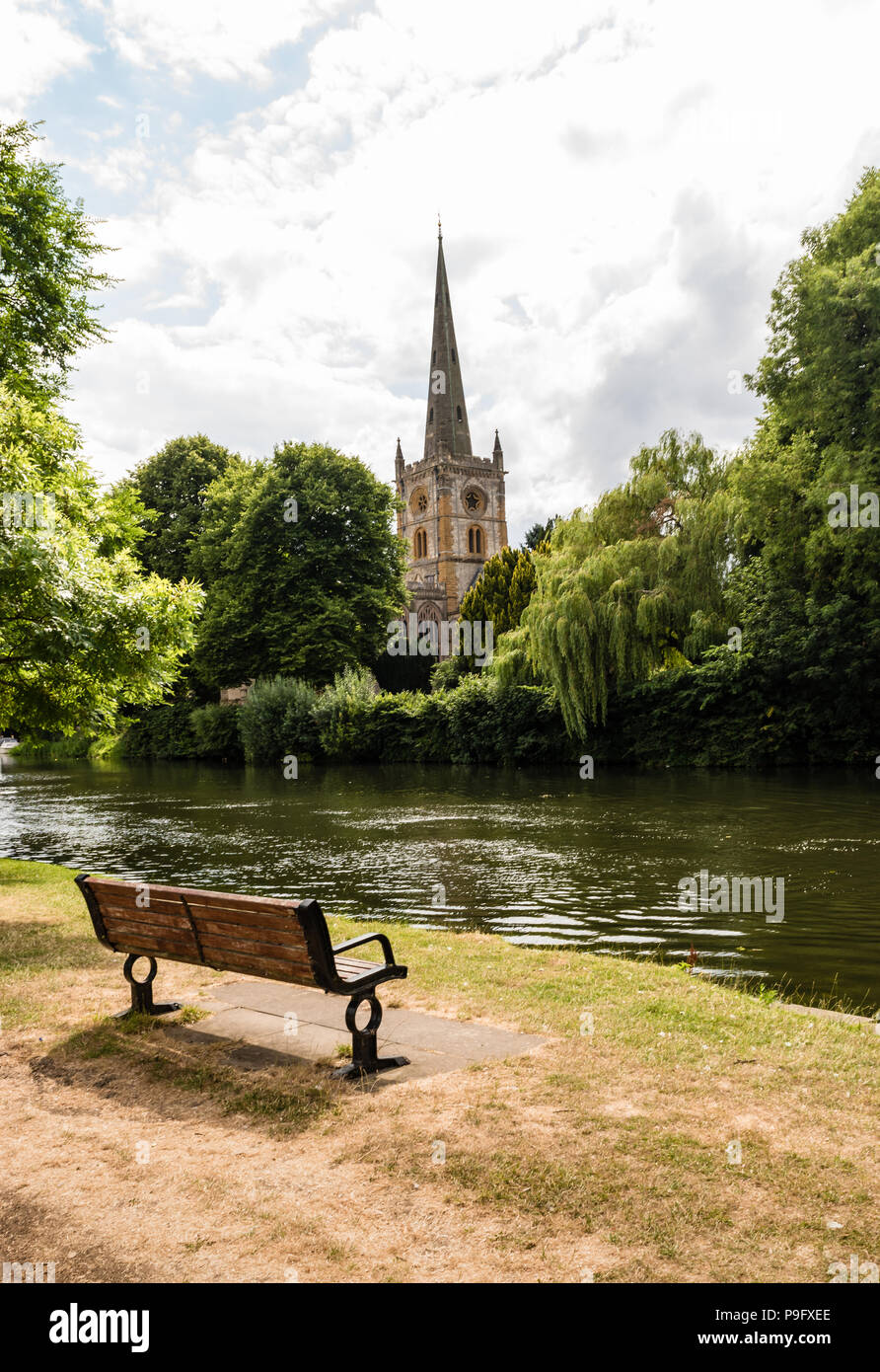 A bench with a view across the river Avon to Holy Trinity church in Stratford upon Avon in England. Stock Photo