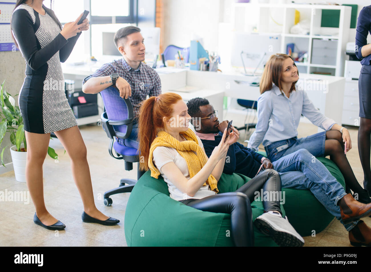 mixed race students are resting on green ottomans in break time. closeup shot Stock Photo