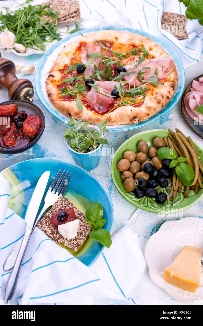 Round large pizza from the oven with prosciutto and olives, arugula and