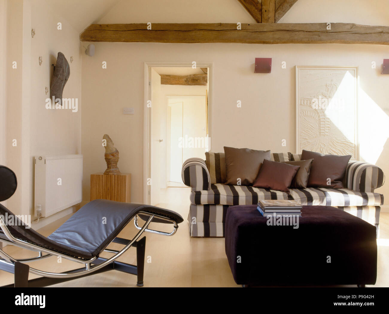 Le Corbusier style black leather and chrome chaise longue in a modern barn  conversion living room with a striped sofa Stock Photo - Alamy