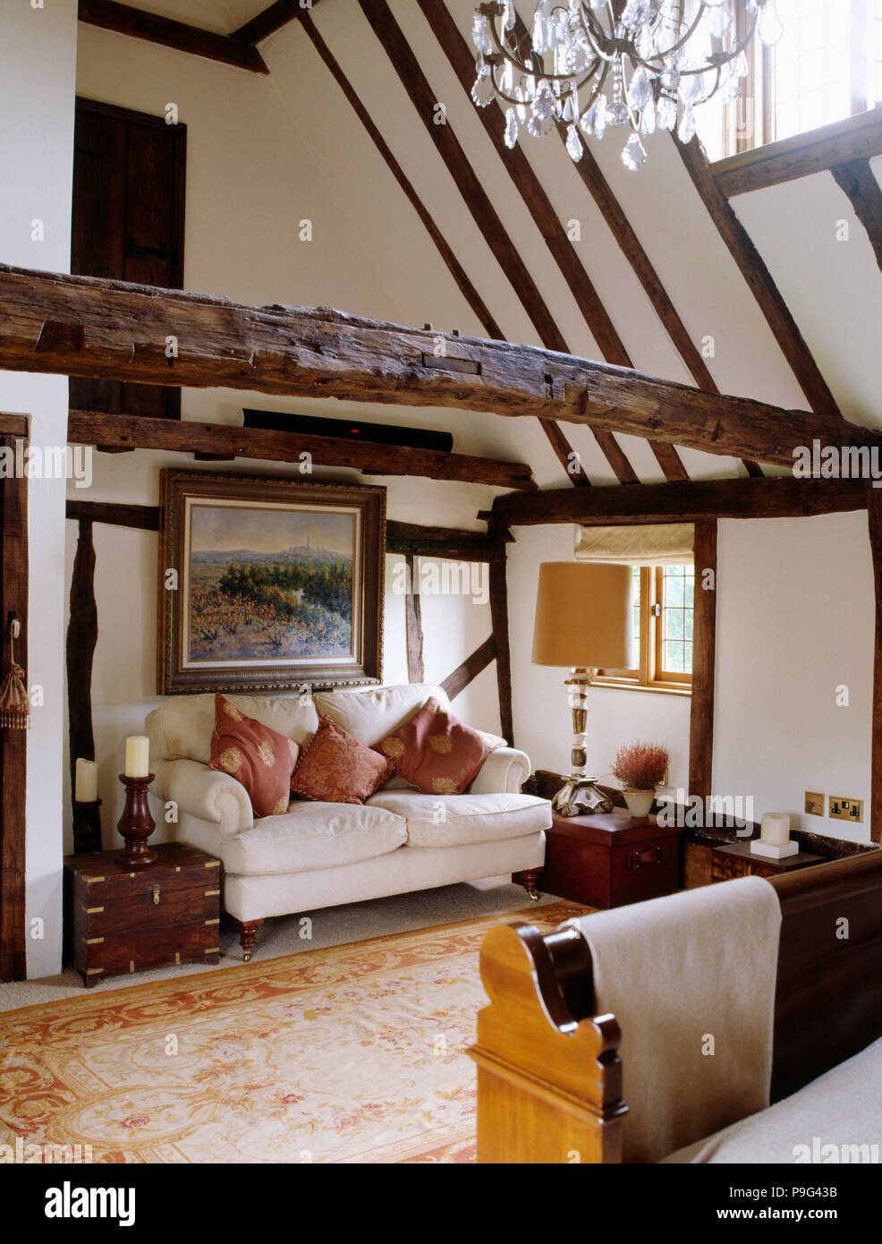 White sofa below large picture in country bedroom with beamed apex White sofa below large picture in country bedroom with beamed apex