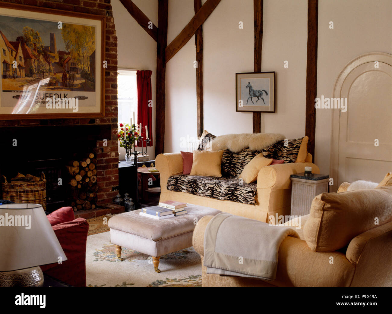 Animal print and sheepskin throws on cream sofas in a cottage sitting room with an ottoman stool Stock Photo