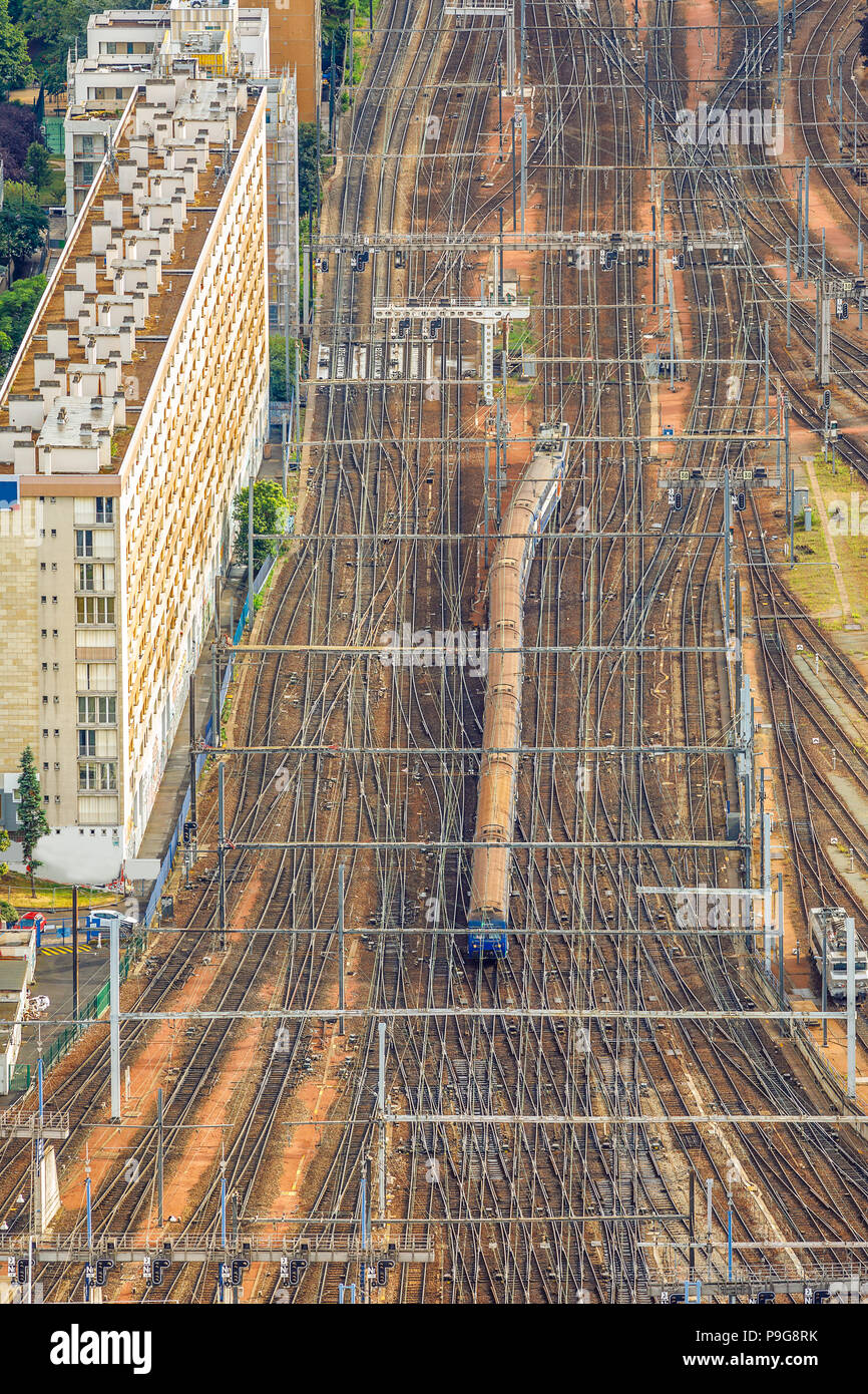 Aerial view of Gare Montparnasse with train from the panoramic overlook from Tour Montparnasse. Paris urban cityscape with rails. Parisian style architecture of France in Europe. Vertical shot. Stock Photo