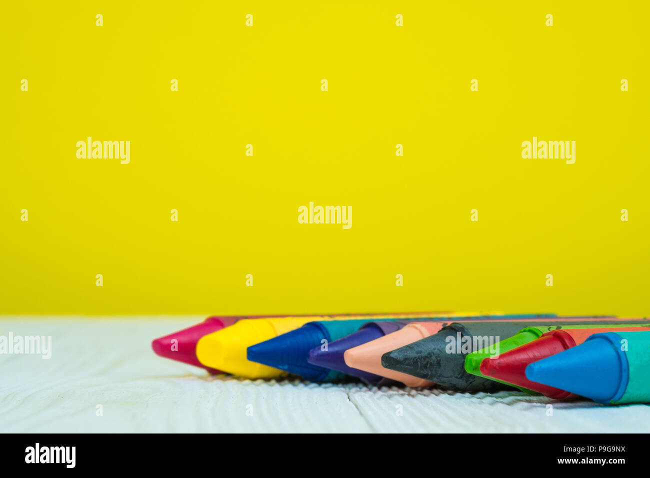 Colourful wax crayons pencils on white wood table with copy space for ...