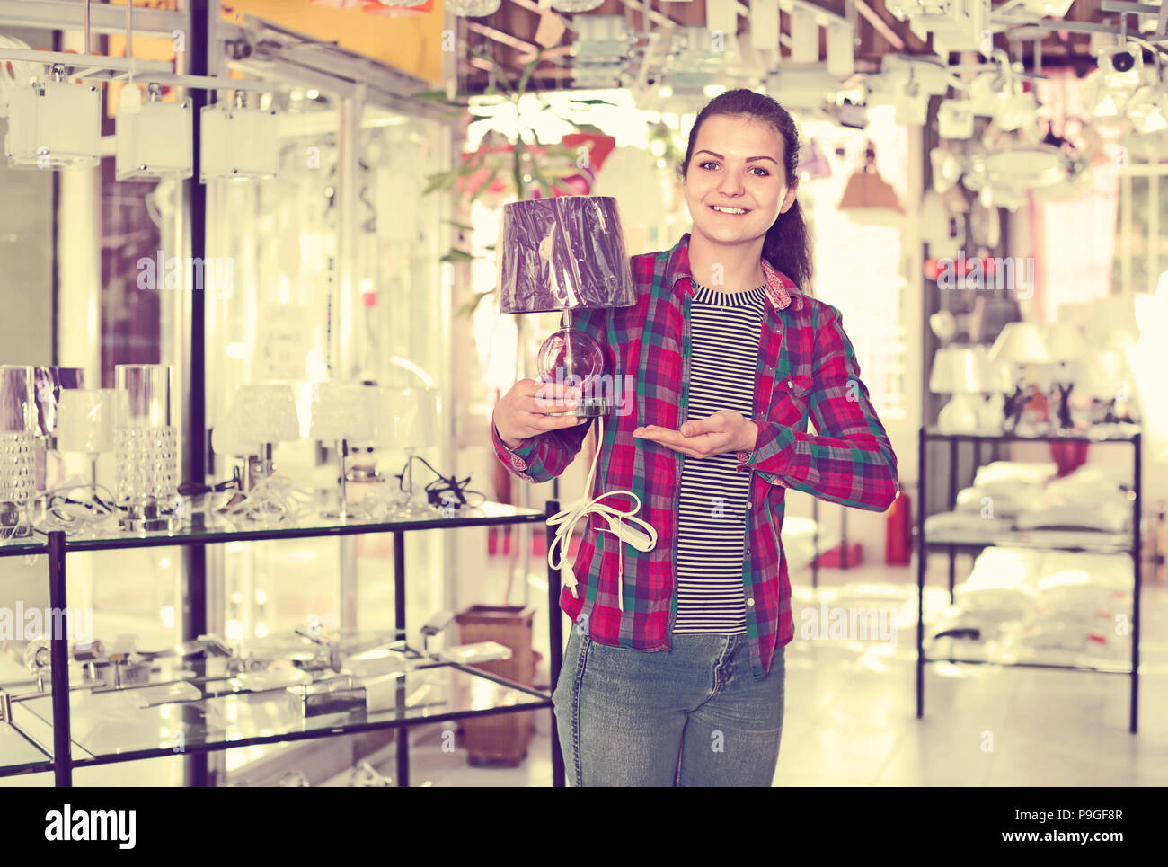 Girl in lighter shop choosing stylish and modern lamp for house