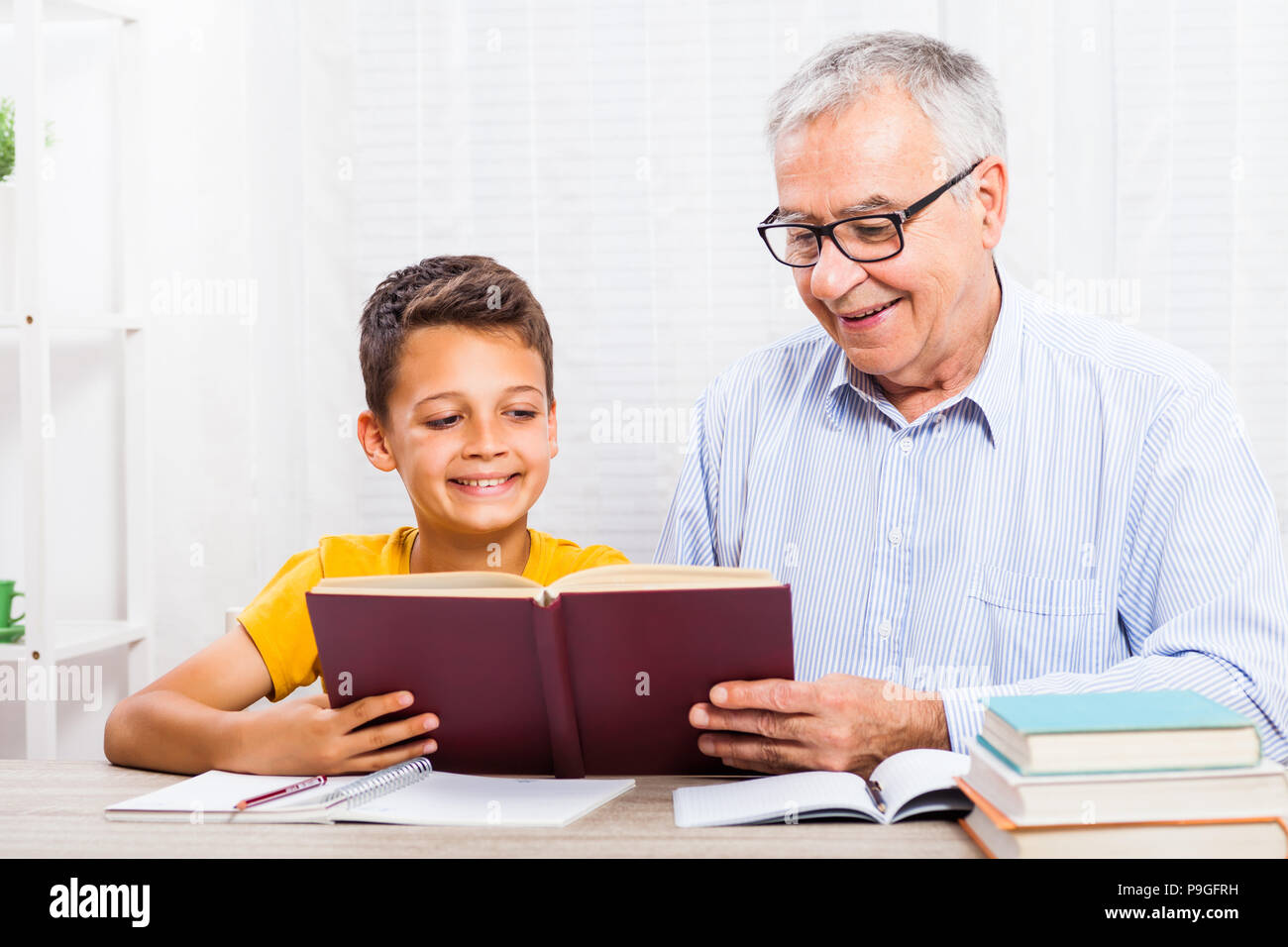 Grandfather and grandson are reading book at home. Stock Photo