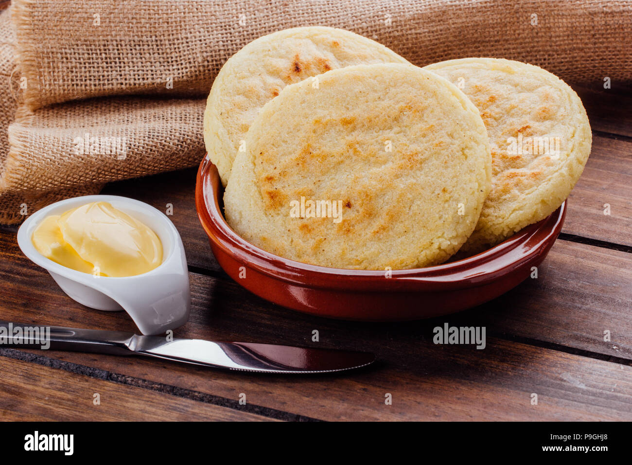 Plate with arepas and butter aside on a rustic wooden background, a ...