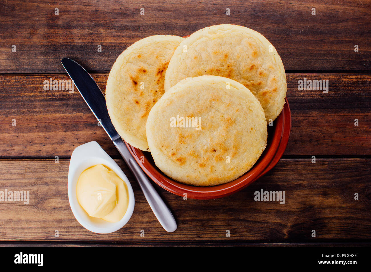 Plate with arepas and butter aside on a rustic wooden background, a ...