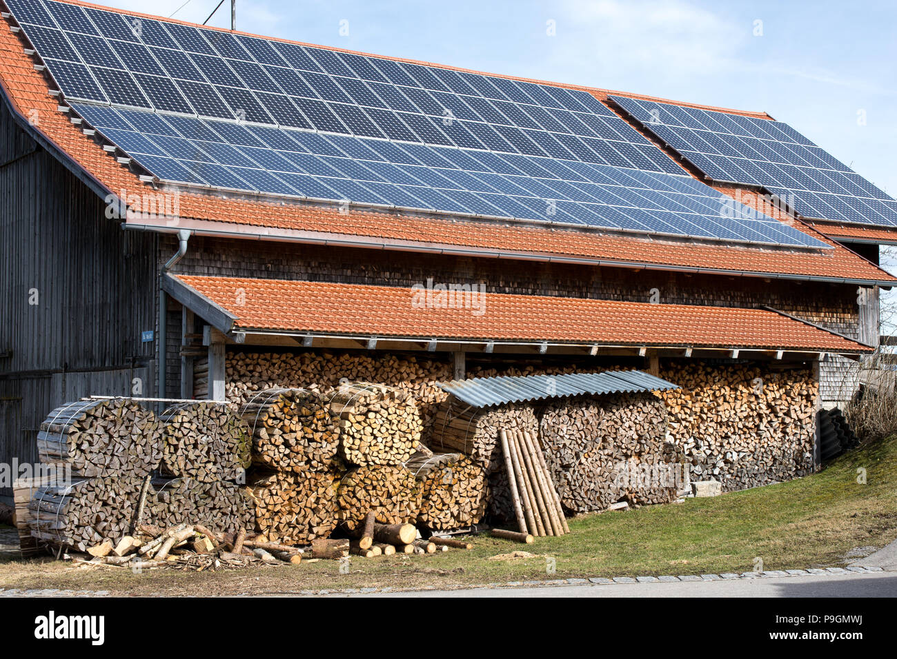 Barn with solar roof and firewood stacks, energy mix Stock Photo - Alamy