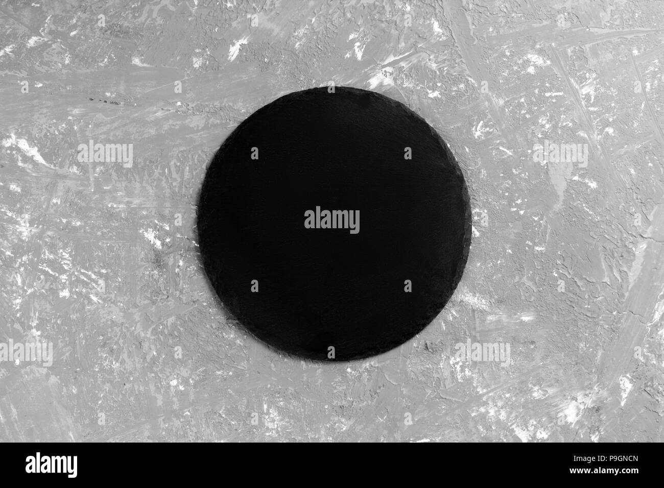 Black empty round slate plate on stone gray background. top view. Stock Photo