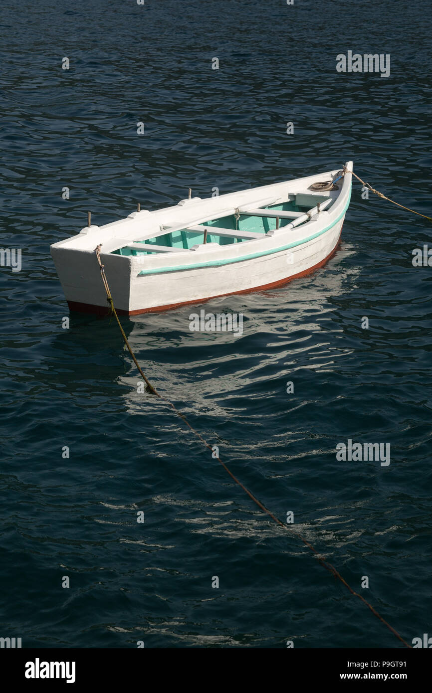 Single isolated small pretty white, green and red wooden rowing boat anchored and floating in the Adriatic Sea at the Bay of Kotor, Perast, Montenegro Stock Photo