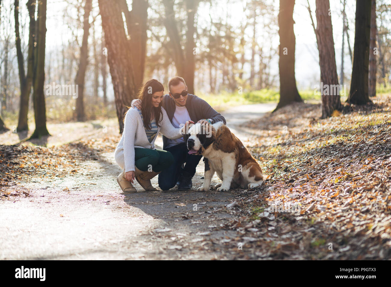 Young couple enjoying nature outdoors together with their Saint Bernard puppy. Stock Photo
