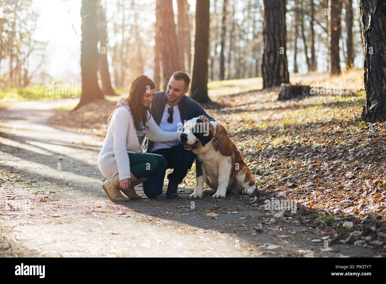 Young couple enjoying nature outdoors together with their Saint Bernard puppy. Stock Photo
