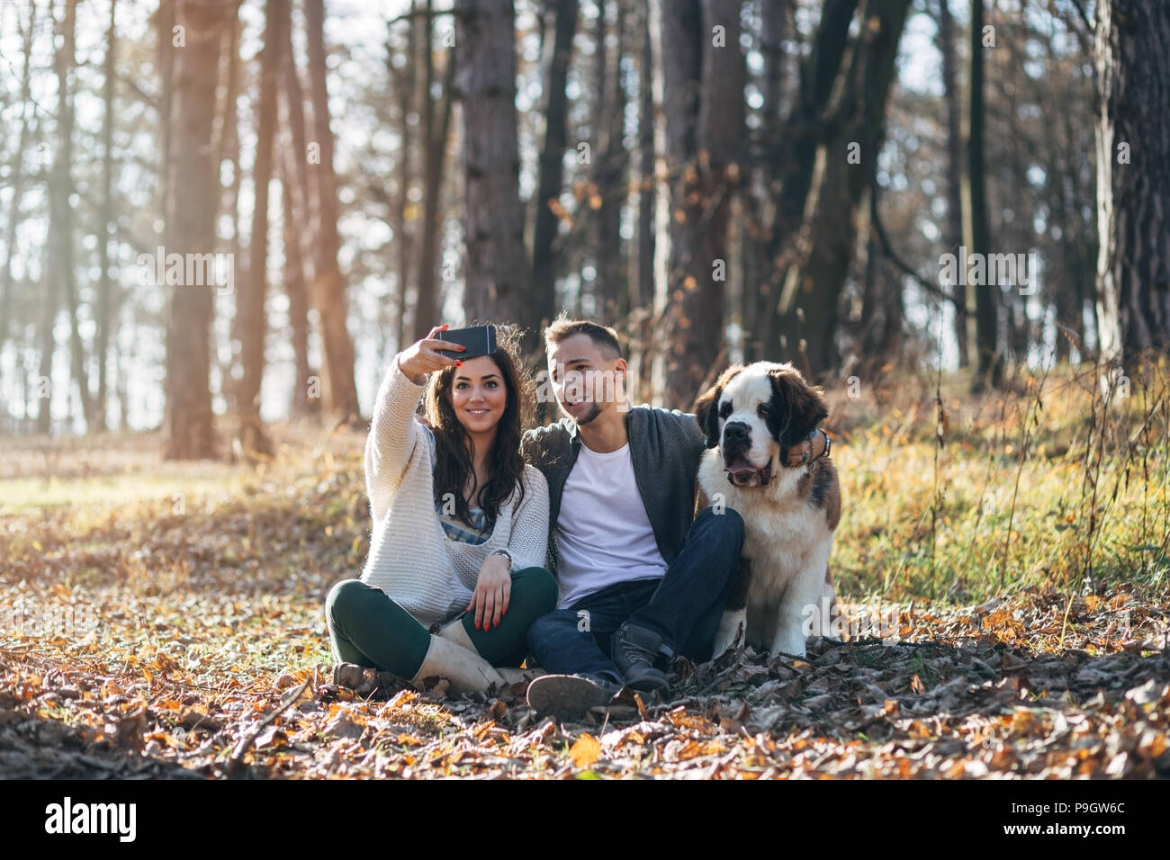 Young couple taking selfie photo with their Saint Bernard puppy. Stock Photo