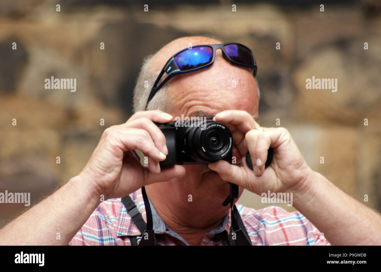 Man wearing sunglasses on his head taking a photograph Stock Photo