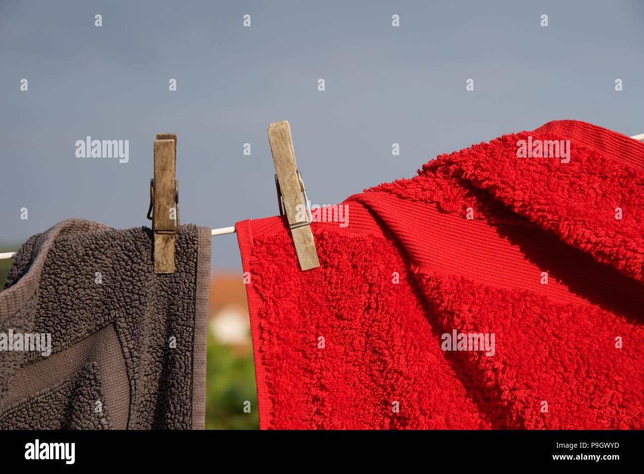 Washing line red and grey towels hung with sprung wooden pegs on a