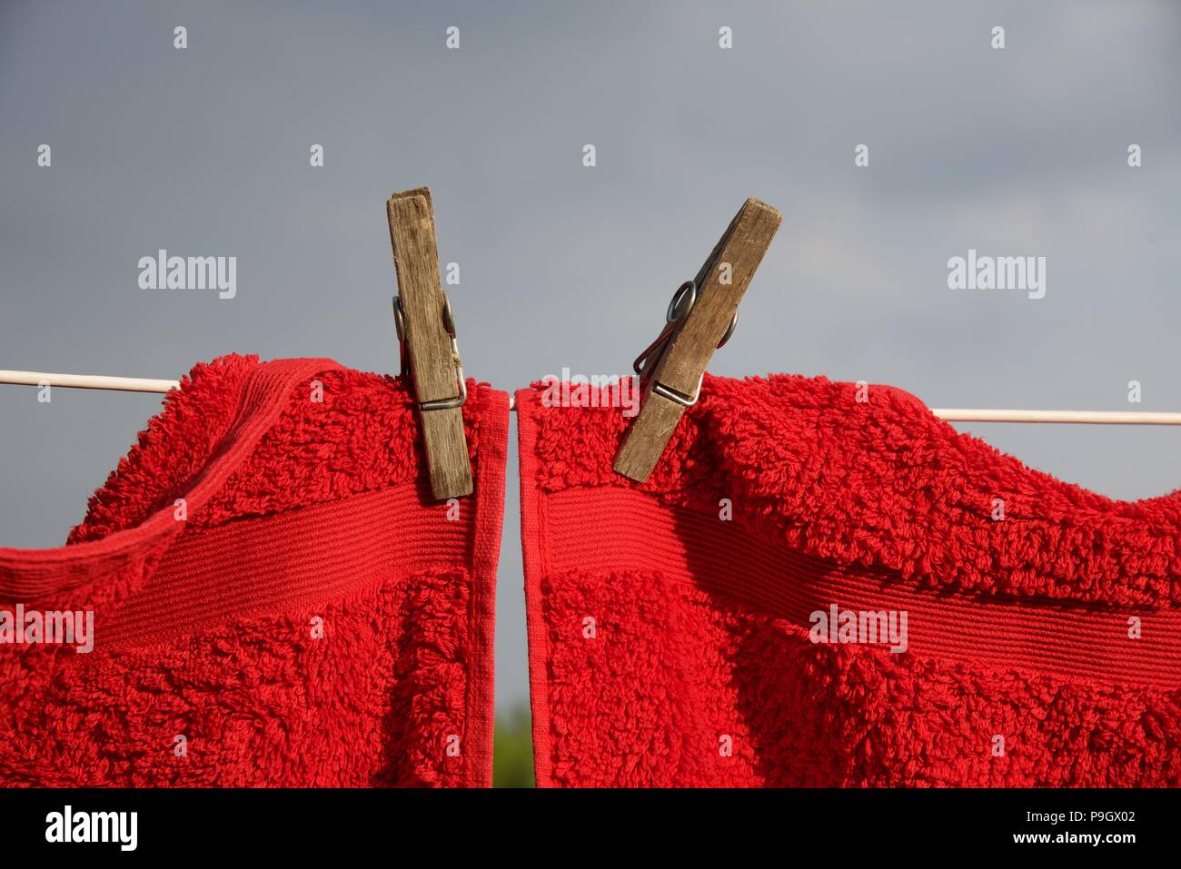 Washing line red and grey towels hung with sprung wooden pegs on a