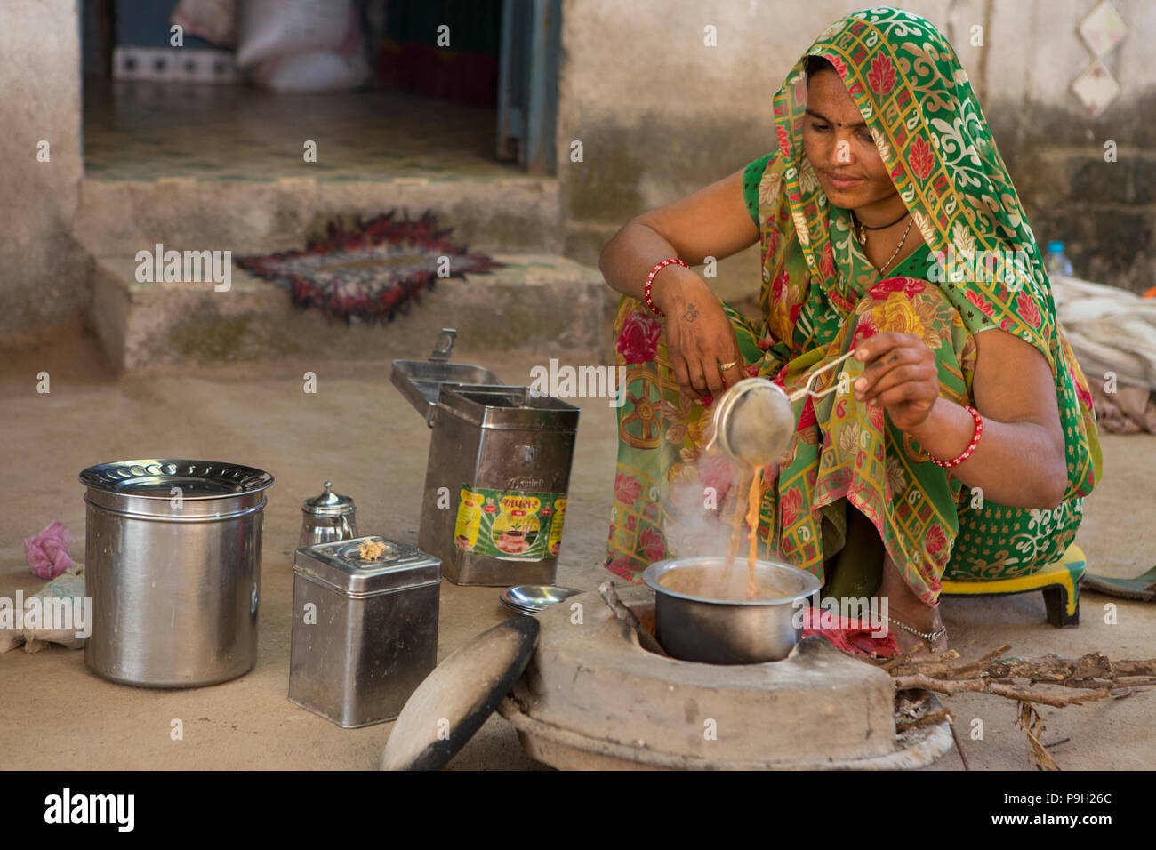 A woman making Indian chai on an open wood fire at their home in Ahmedabad, India. Stock Photo