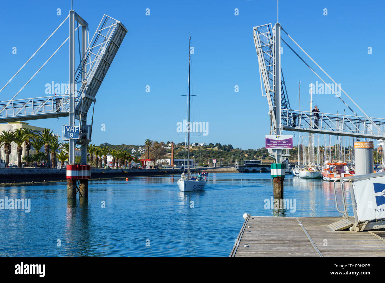 A sailing boat motors through the bascule bridge over the river Bensafrim by the Lagos Marina (Marina de Lagos), Portugal. Beautiful blue skies Stock Photo