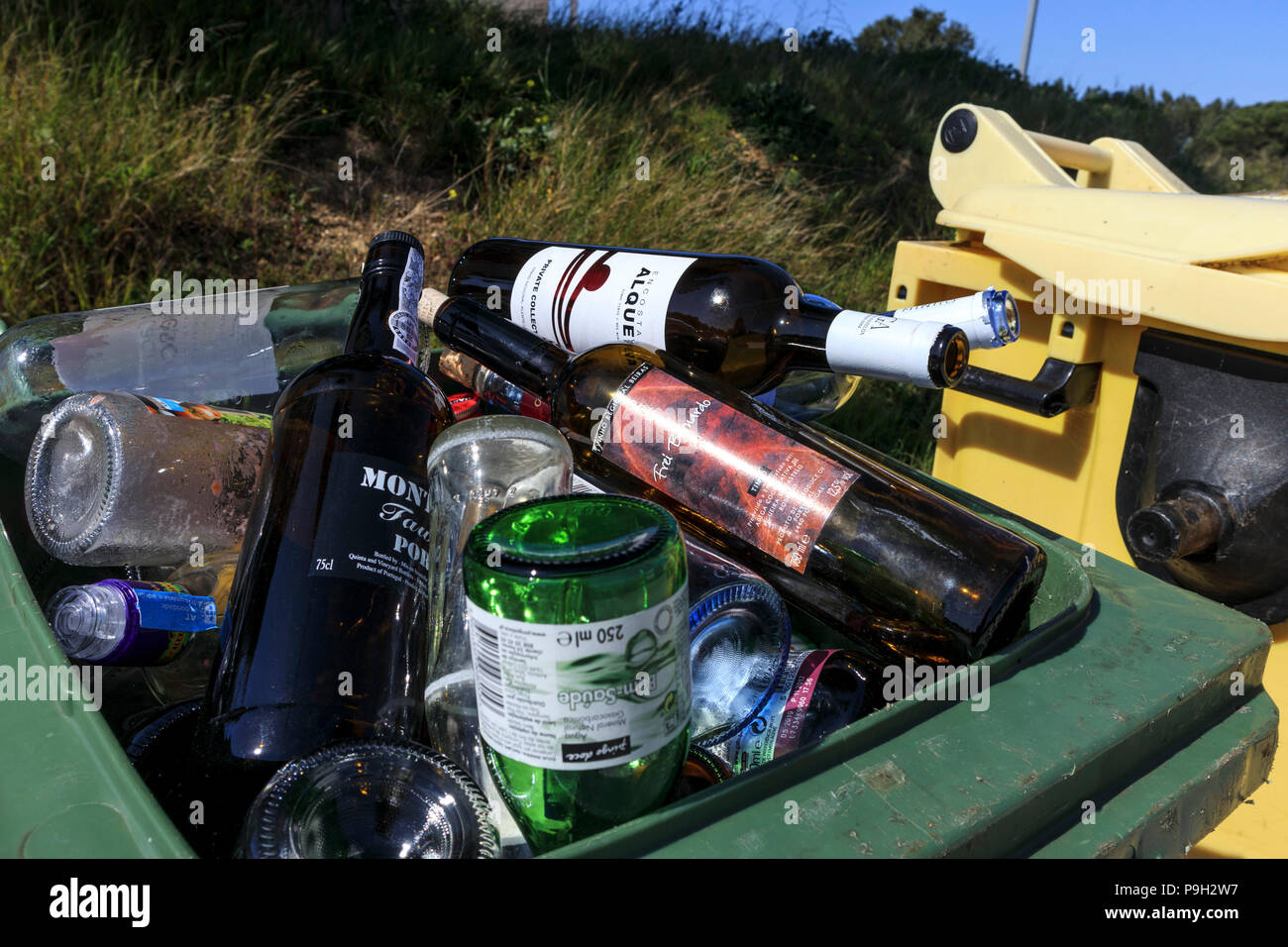 Recycling trash bin piled full of empty glass bottles Stock Photo