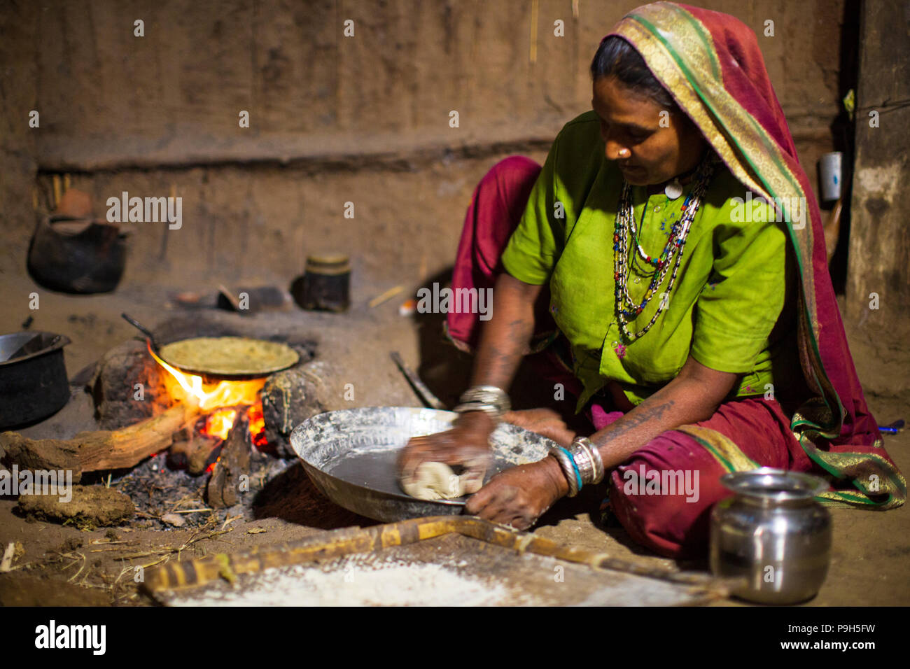 A woman making chapatis on an open fire in her kitchen, Sendhwa, India. Stock Photo