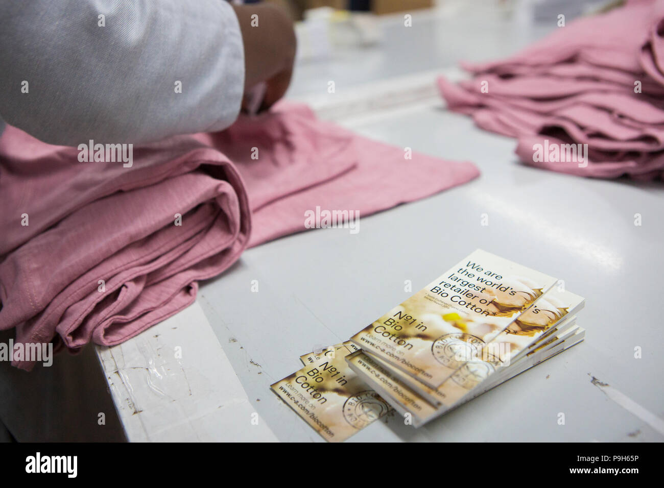 A Bio Cotton label being fixed on T-shirts in a garment factory where organic cotton is being used to make clothes, Indore, India. Stock Photo