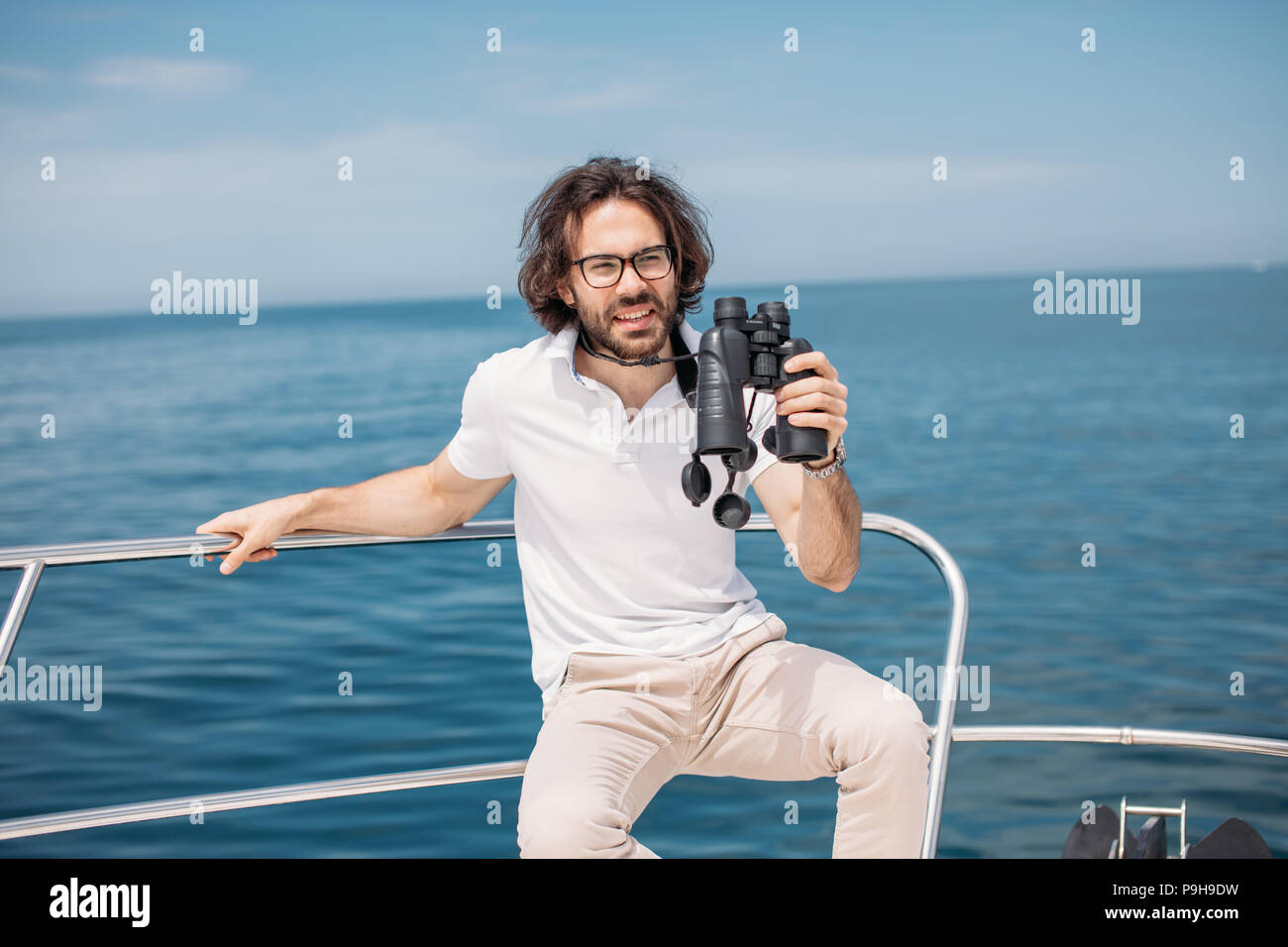 European Bearded Yachtsman Looking Through Binoculars From The Boat In european-bearded-yachtsman-looking-through-binoculars-from-the-boat-in