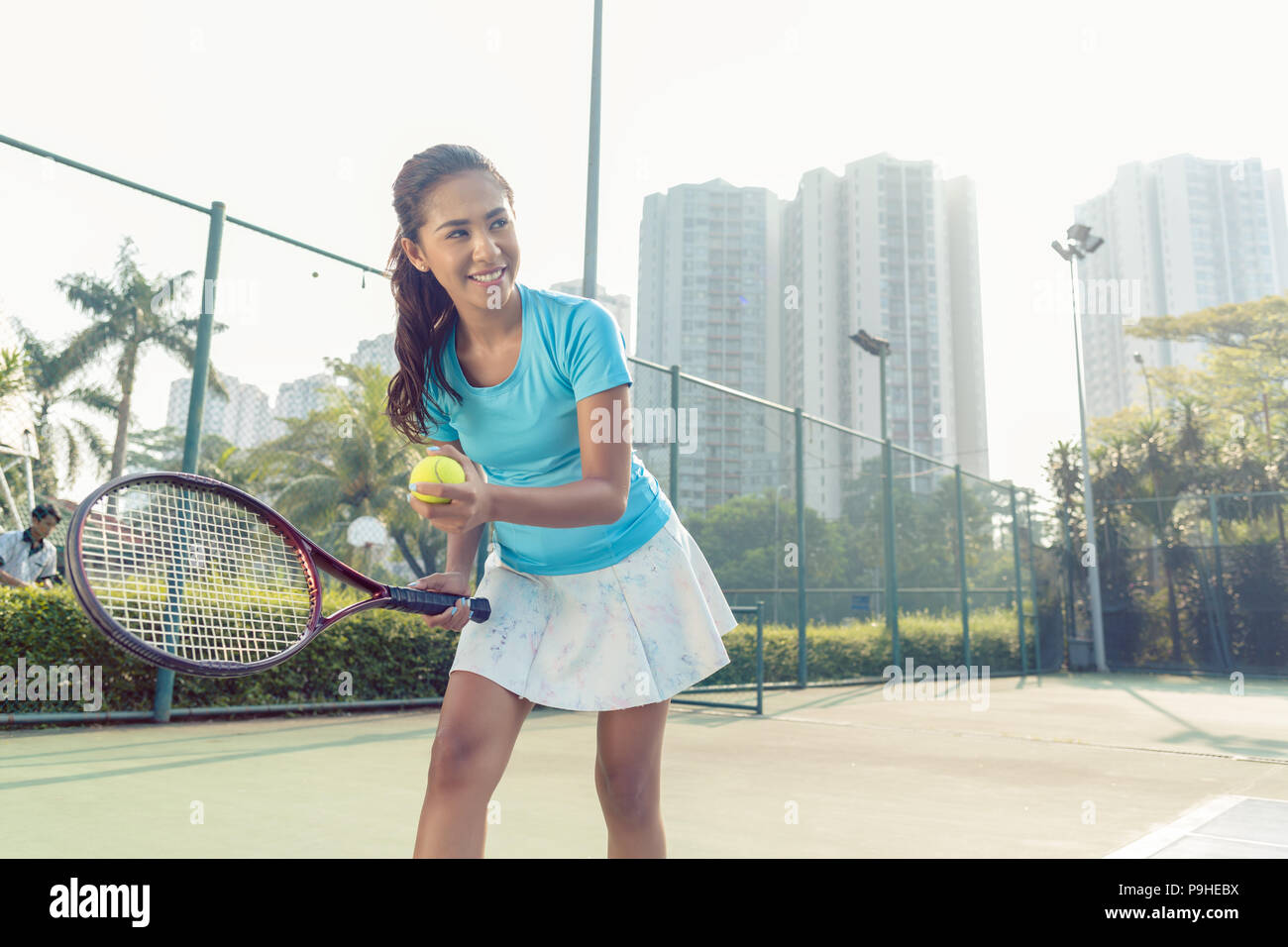 Professional female player smiling while serving during tennis match Stock Photo