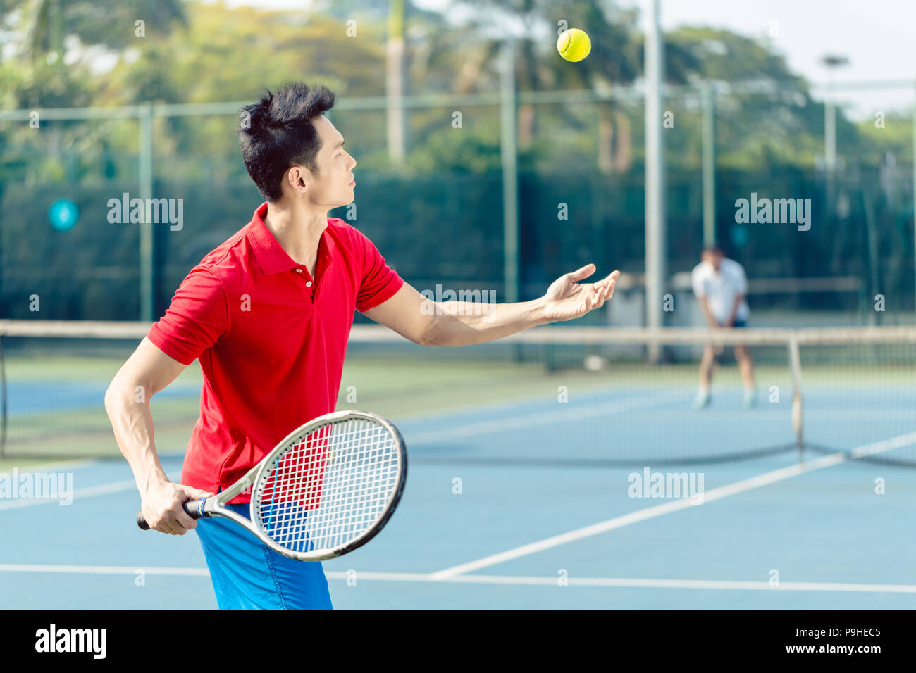 Chinese tennis player ready to hit the ball while serving in a tennis match Stock Photo
