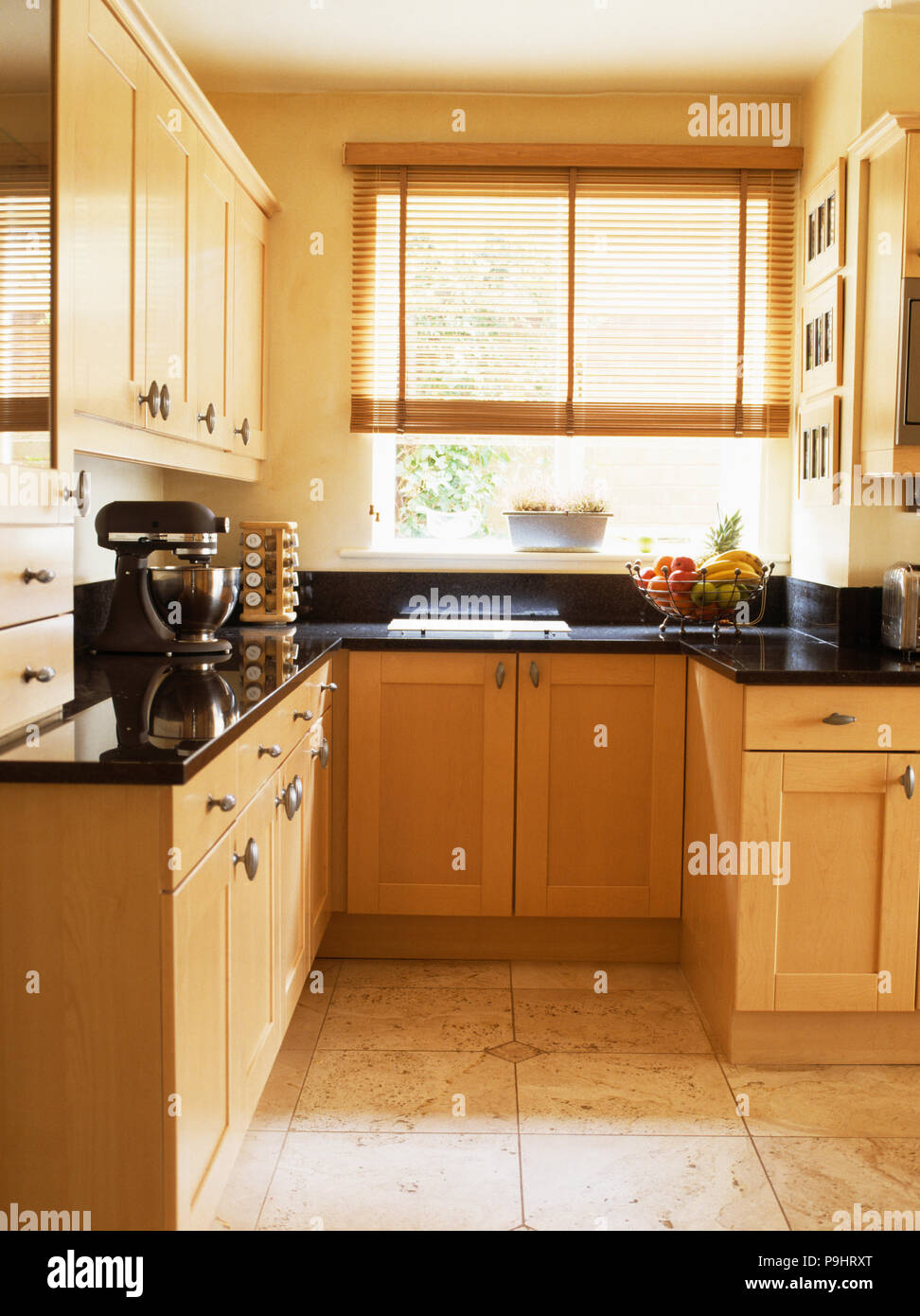 Pale Wood Fitted Units In Small Modern Kitchen With Cane Blind On