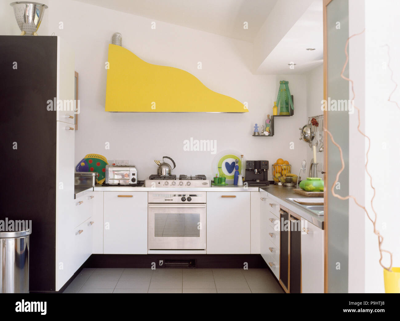 Modern white kitchen extension with extractor fan hidden behind yellow boarding Stock Photo