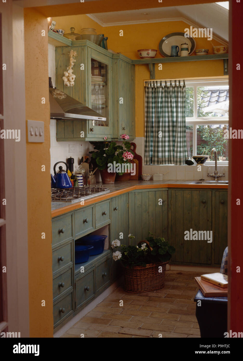Pastel Green Cupboards And Units In Small Pale Orange Kitchen Extension With Green Checked Curtains Stock Photo Alamy