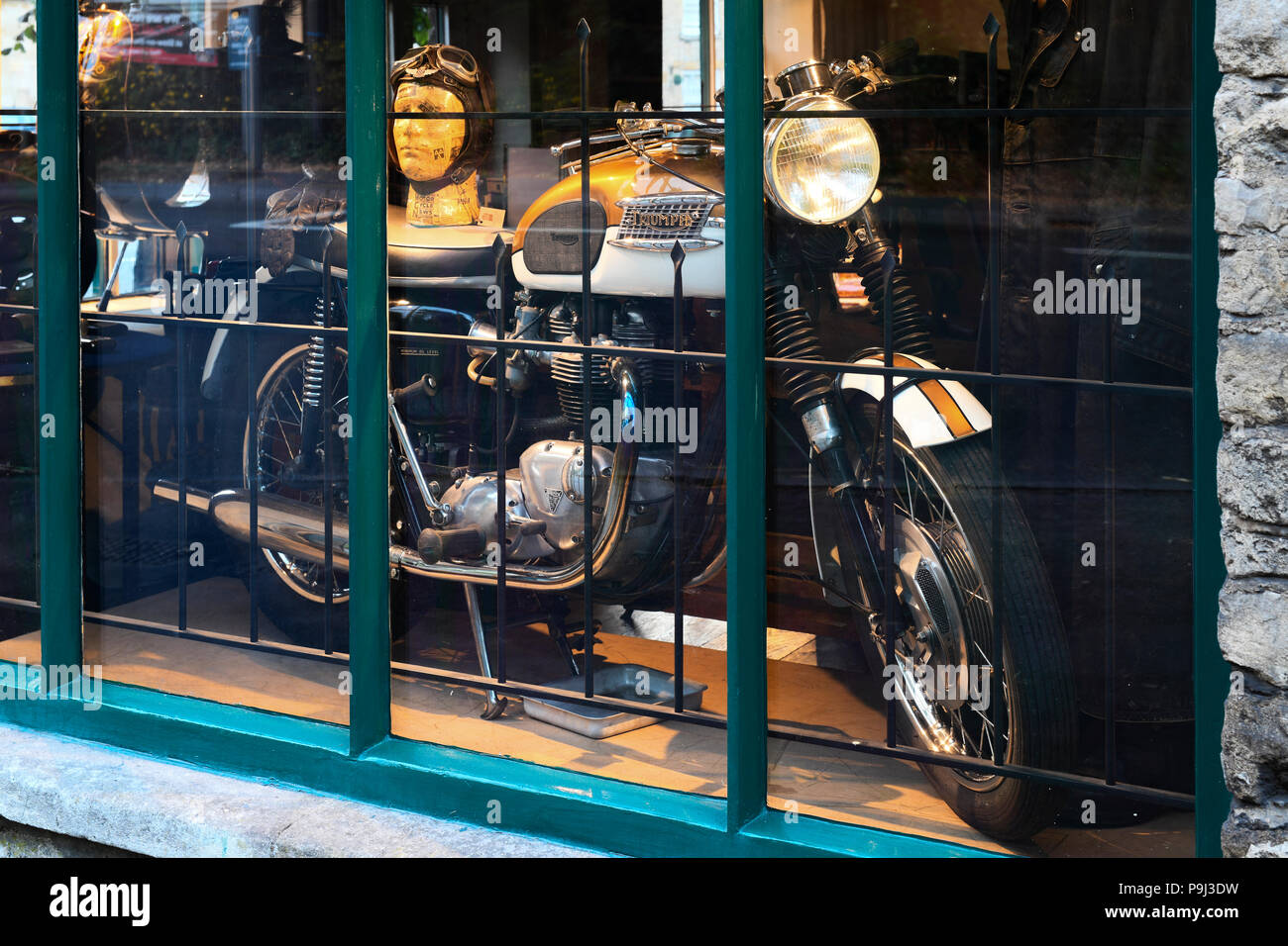 Vintage triumph motorcycle on an antiques shop window display in Stow
