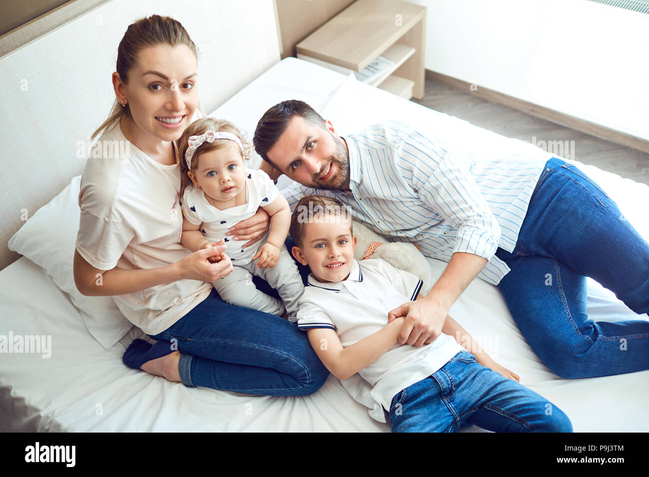 Happy family  playing lying on the bed in the bedroom. Stock Photo