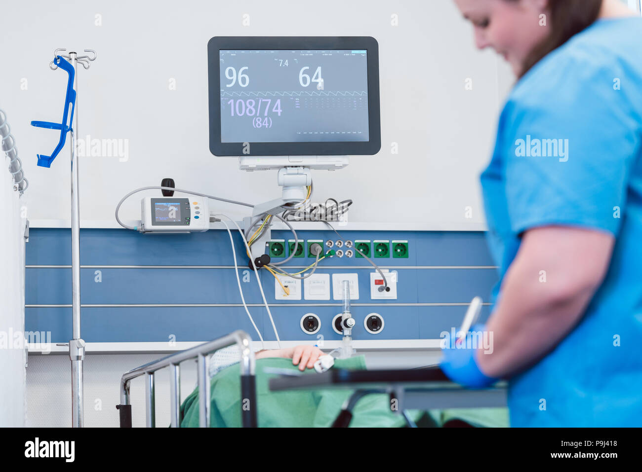 Nurse monitoring patient after operation in recovery room Stock Photo