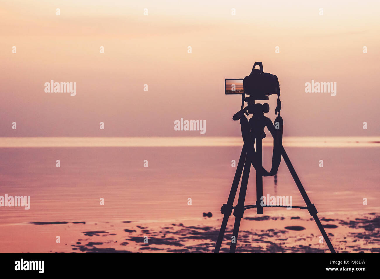 Dslr digital professional camera stand on tripod photographing sea, twilight sky and cloud landscape. nature background.image,picture on screen. dslr  Stock Photo