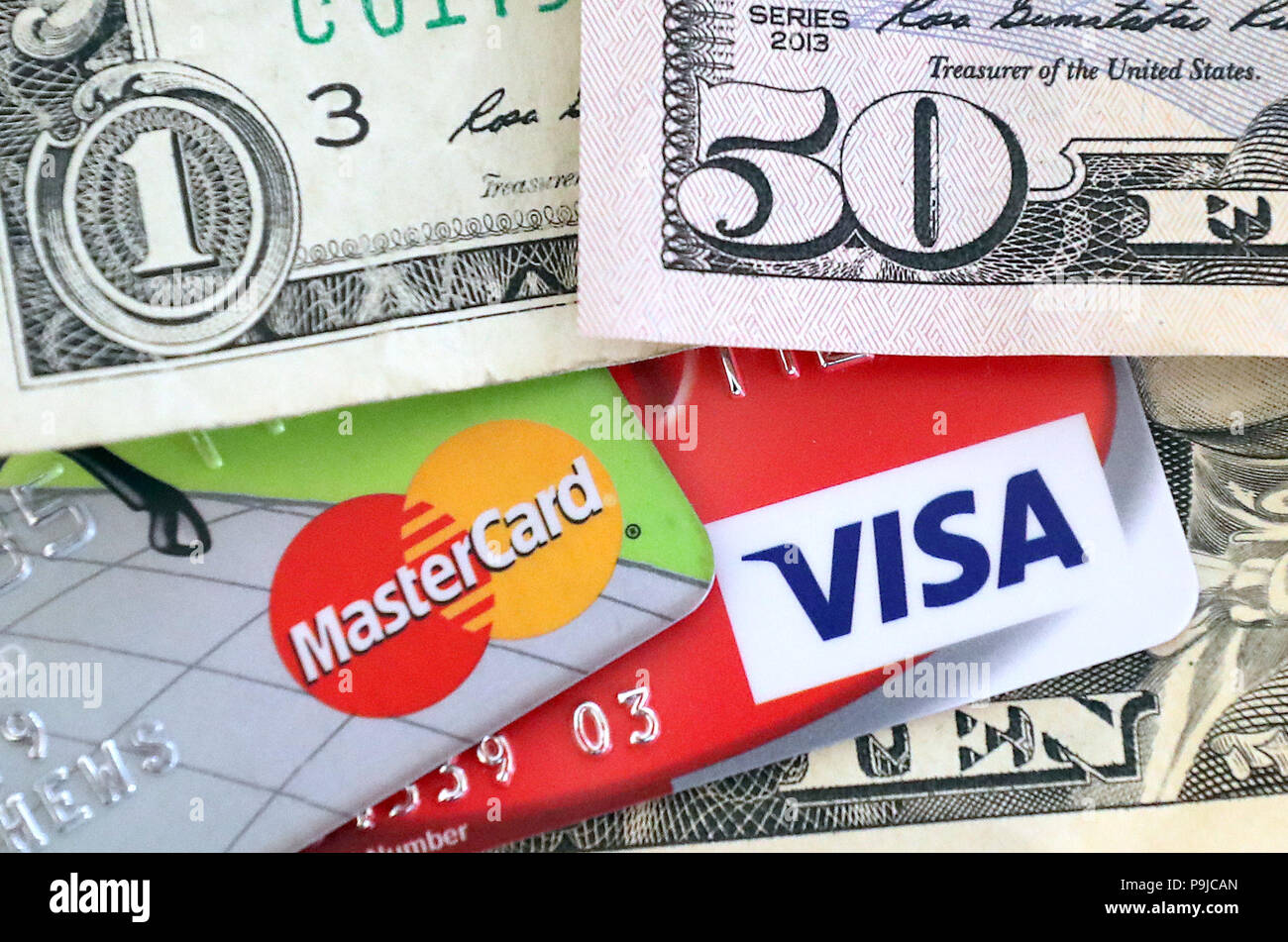A Mastercard credit and Visa debit cards surrounded by US Dollars Stock Photo
