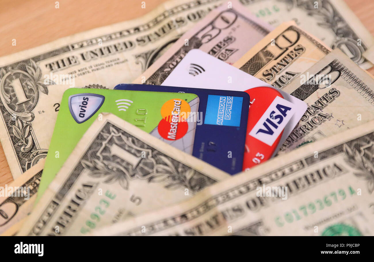 A Mastercard, American Express and Visa credit and debit cards surrounded by US Dollars Stock Photo