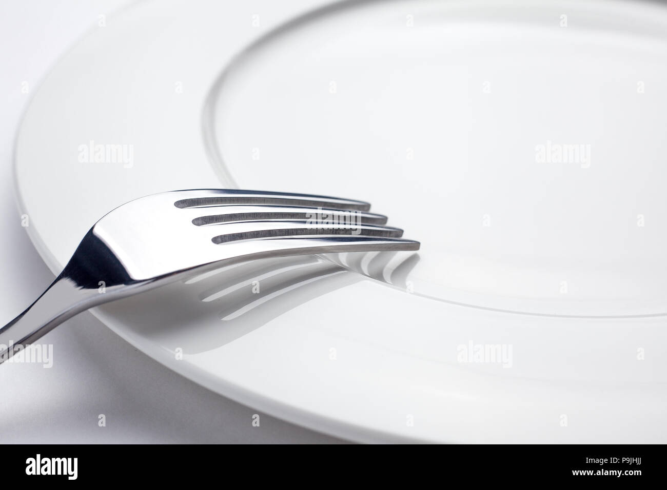 Fork on a empty plate, cutlery and copy space, on a white background Stock Photo