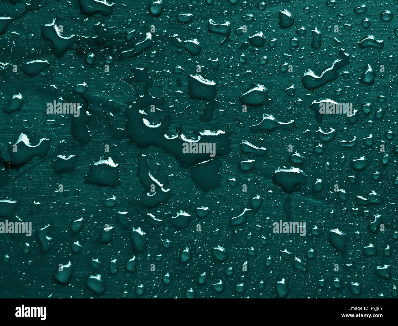 water drops on quetzal green colored metallic surface Stock Photo