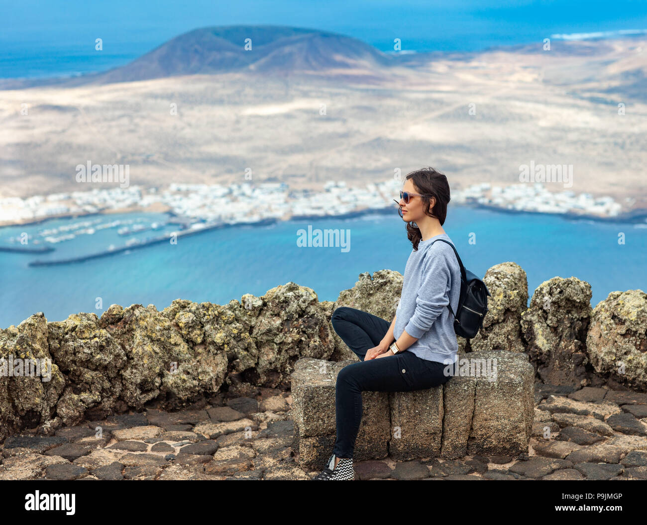 Traveler woman enjoying at viewpoint on island. Travel vacation concept. La Graciosa Island, Mirador del Rio, Lanzarote, Canary Islands, Spain. Stock Photo