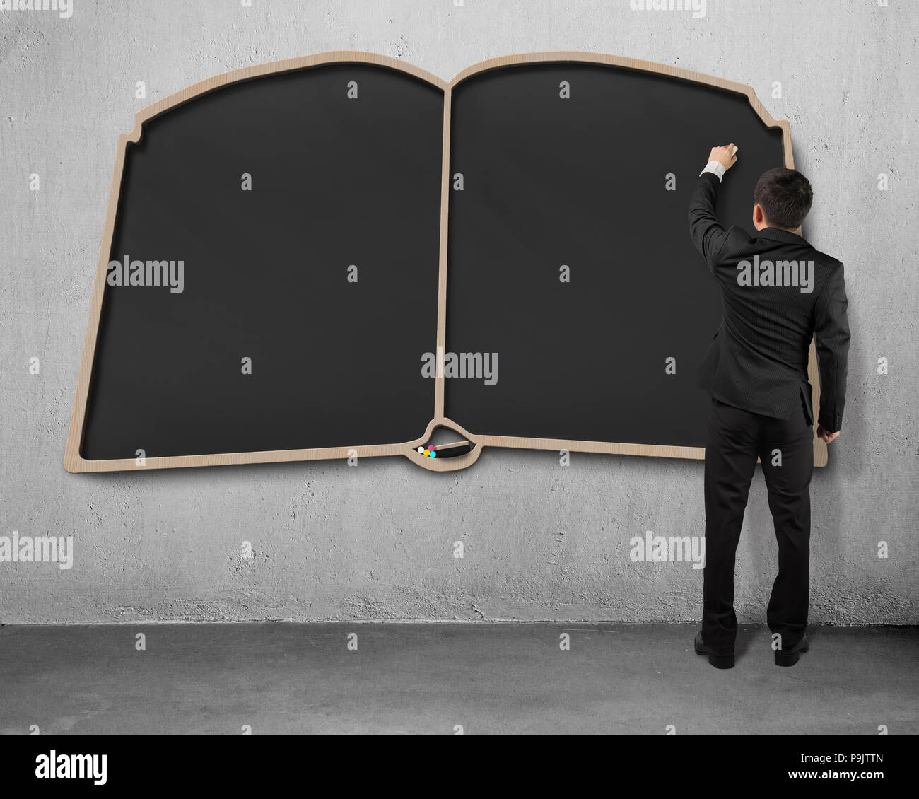Man writing on book shape blackboard Stock Photo