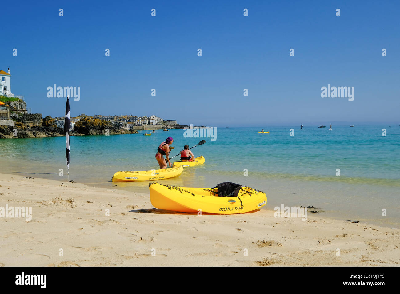 A couple setting off in yellow kayaks at Porthminster Beach in St Ives, Cornwall Stock Photo
