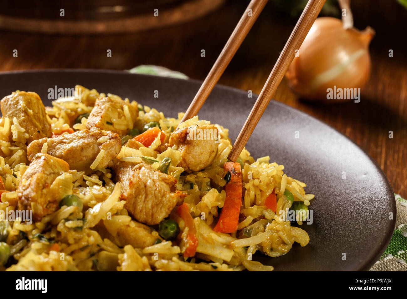 Fried rice nasi goreng with chicken and vegetables on a plate. Indonesian cuisine. Stock Photo